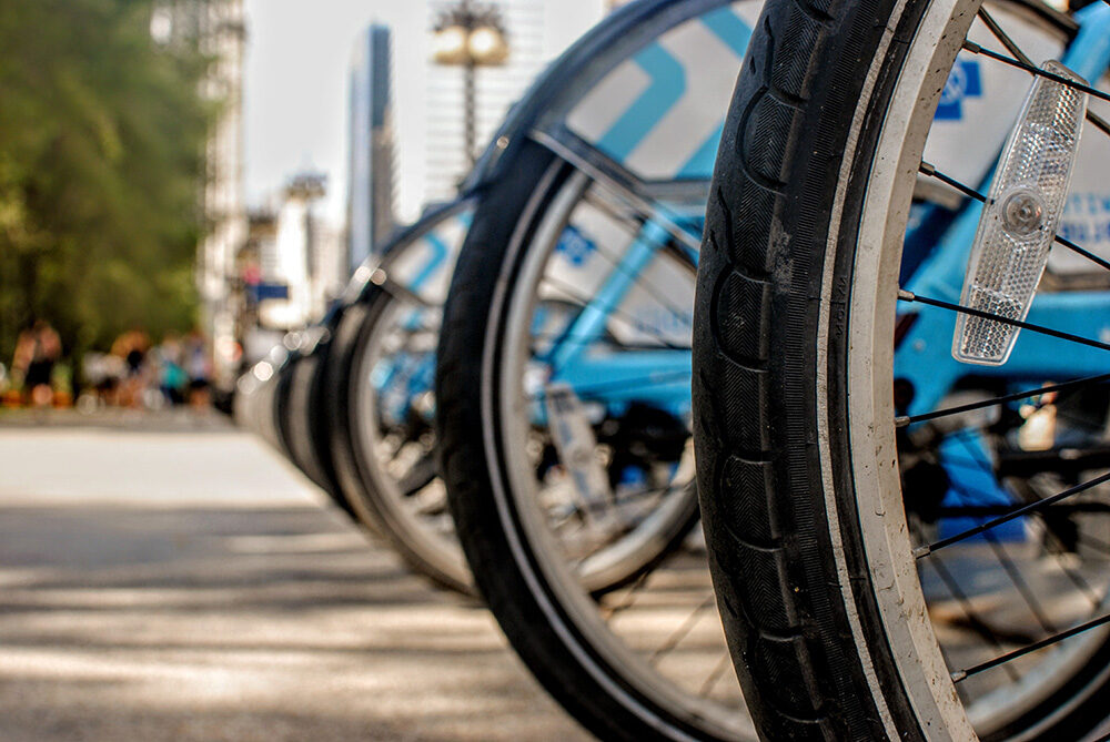 Close-up of bike tires on bikes, linked up in a row on a sidewalk.