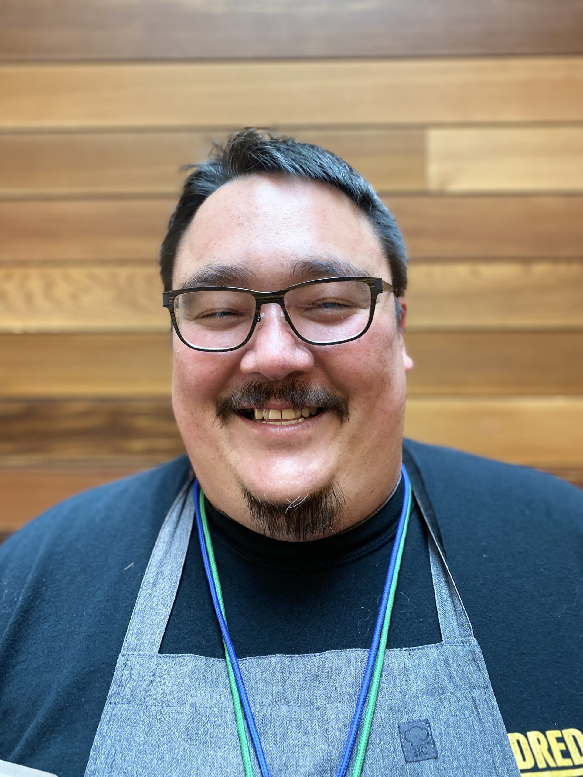 Photo of a man with glasses and apron, smiling at the camera.